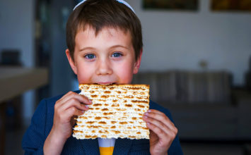 Cute Caucasian Jewish boy holding in his hands and taking a bite