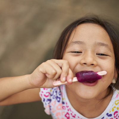 Asian girl eating ice cream in outdoor. Filipina kid eating an ice cream and staring at camera.