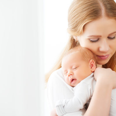 newborn baby in a tender embrace of mother at the window